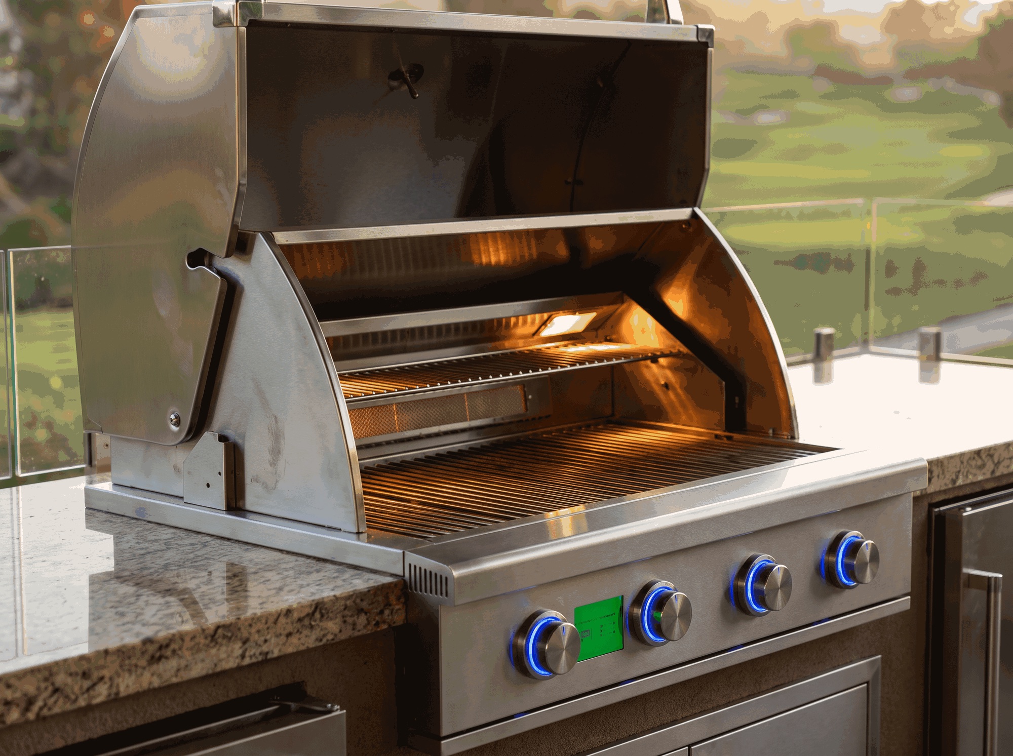 Close-up of a stainless steel JetKev grill, lid open and interior glowing, with illuminated blue control knobs